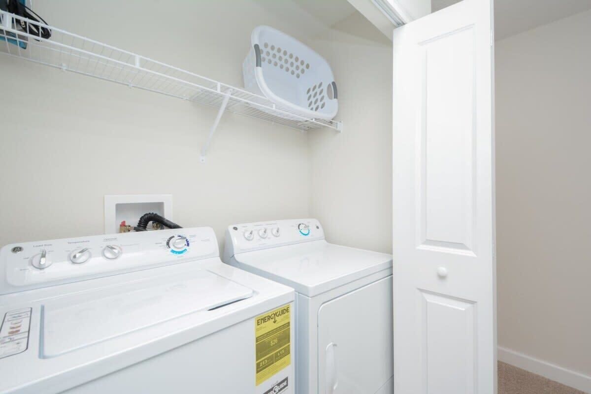 Un cuarto de lavado con dos lavadoras blancas, un tendedero y una puerta cerrada.