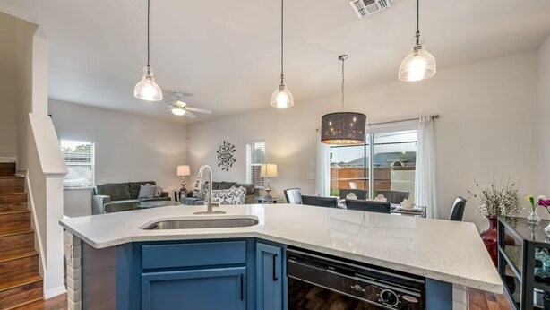 A modern kitchen with a large island, blue cabinets, and pendant lighting. - Remodeled Gem - Comfort and Location (Kissimmee)