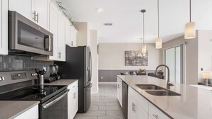 Una cocina moderna con electrodomésticos de acero inoxidable, una isla central e iluminación colgante.