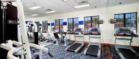 Ein Fitnessstudio mit Laufbändern, Crosstrainern und Gewichten.
