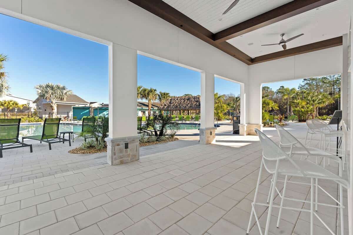 An outdoor patio area with white chairs and a pool in the background.