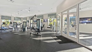 Ein modernes Fitnessstudio mit unterschiedlichen Trainingsgeräten, großen Fenstern und einem hellen, sauberen Innenraum.
