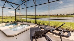 Un espacio exterior cubierto con vidrio, que incluye un jacuzzi, sillones de descanso y vistas a un lago.