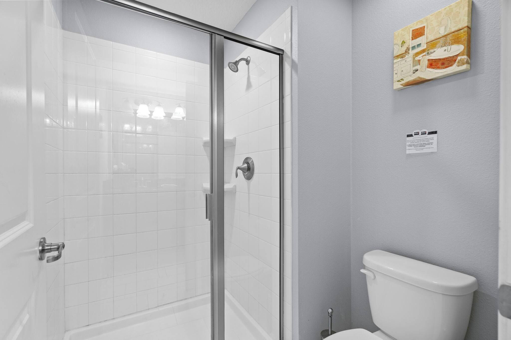 A bathroom with a glass shower enclosure, a toilet, and a wall-mounted sink.