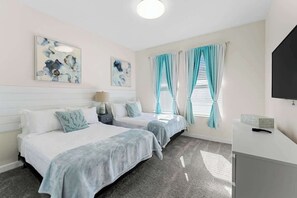 A hotel room with two beds, a desk, a TV, and artwork on the walls. - Sophisticated 6BR at Storey Lake (Kissimmee)