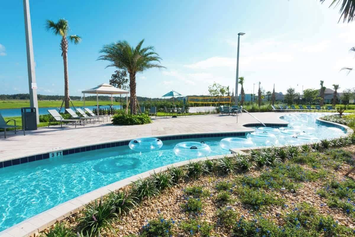 Una piscina con sillas de descanso y una palmera.