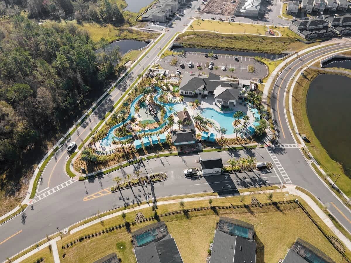 Eine Luftaufnahme eines Resorts mit Schwimmbad, Parkplatz und umgebender Bepflanzung.