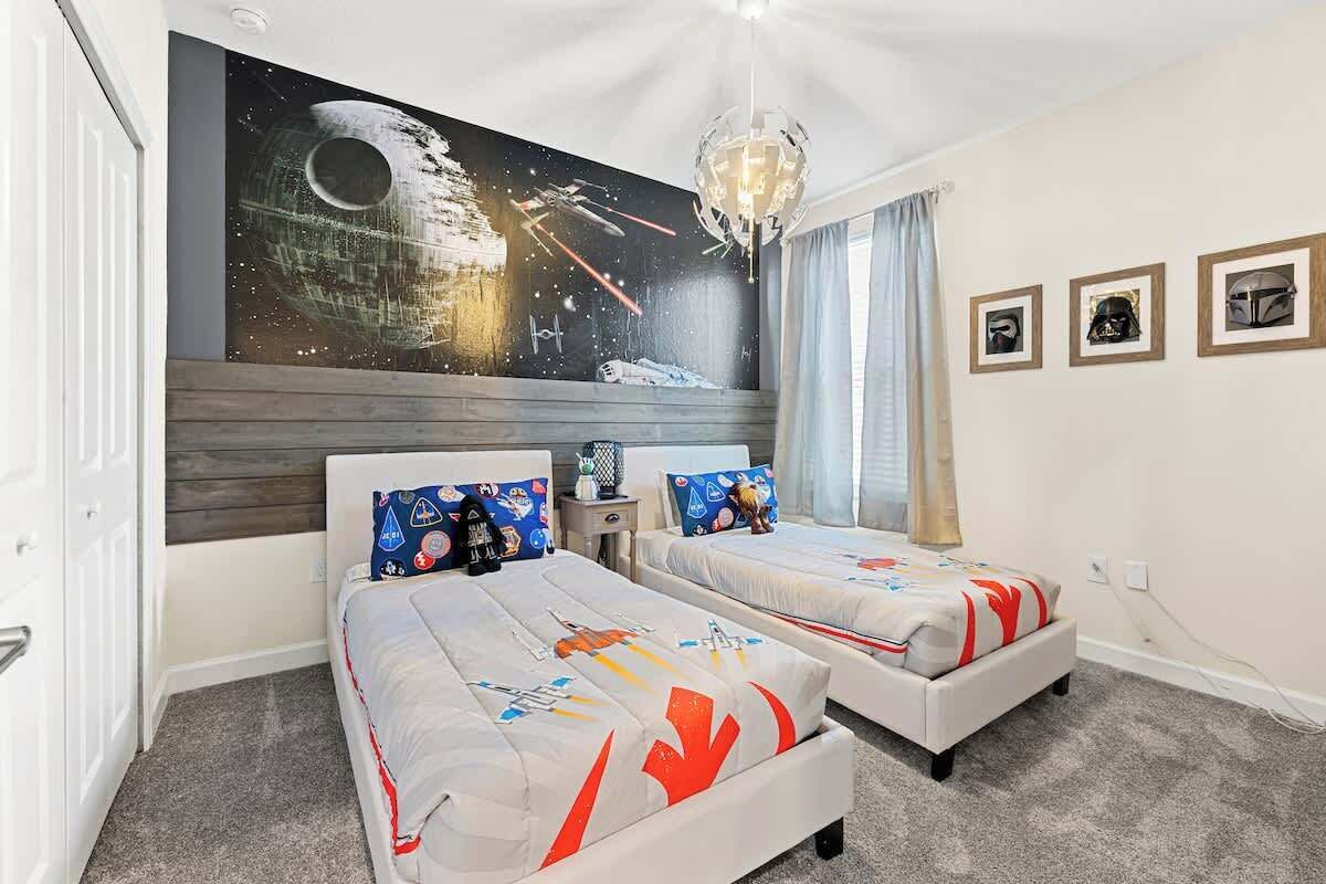 A hotel room with two beds, a mural of a space scene, and framed pictures on the wall.