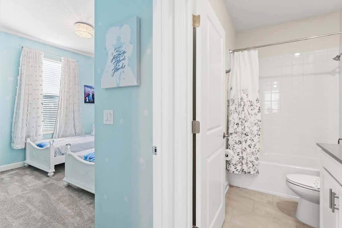 A bedroom with a bed, a window with curtains, and a wall with a framed quote.