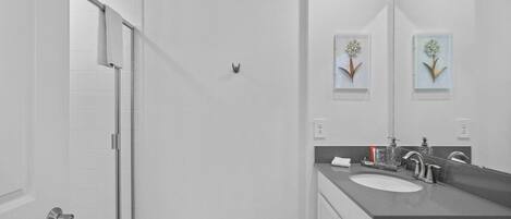 Un baño con ducha, lavabo y espejo.