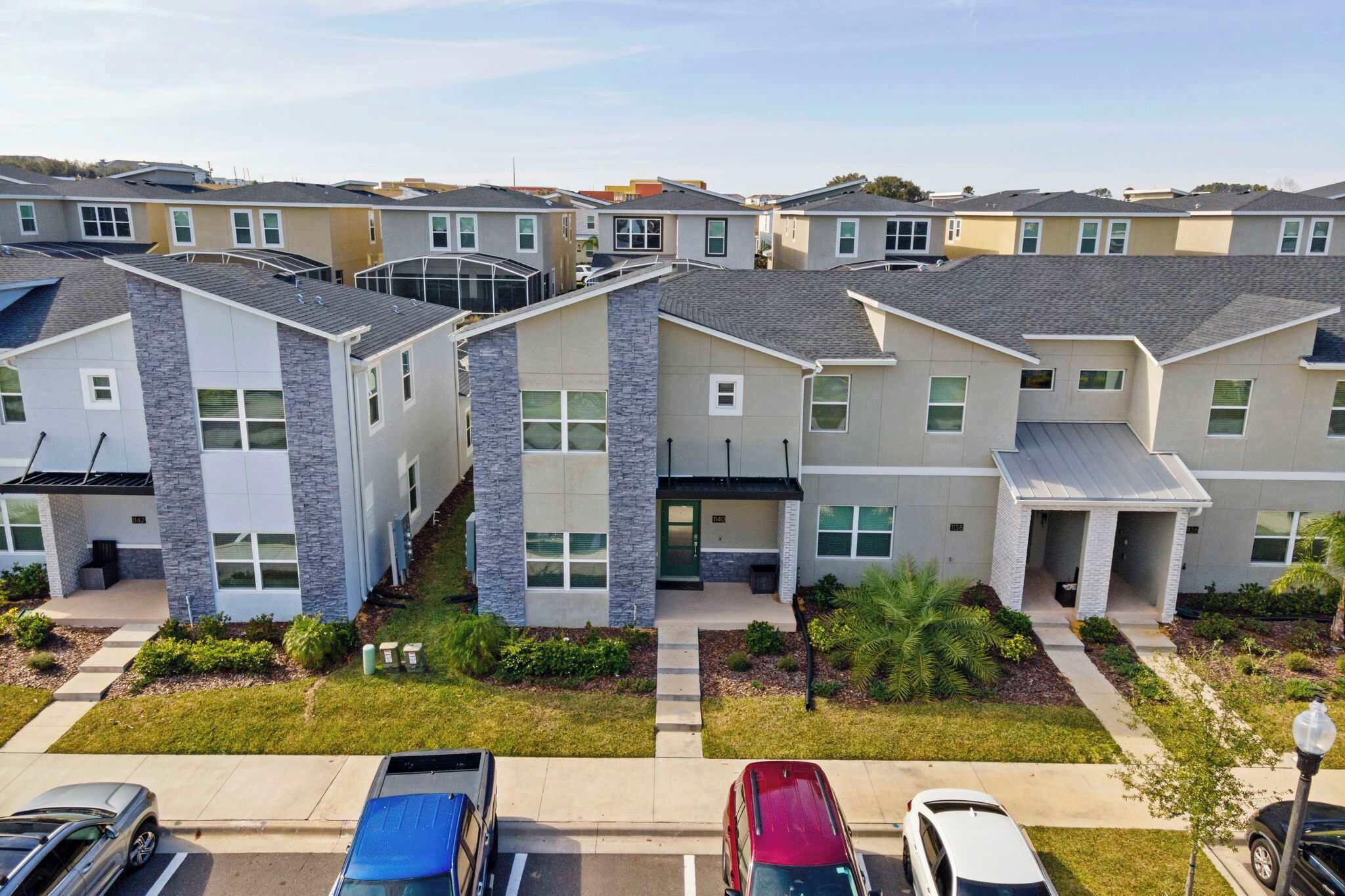 A residential complex with multiple townhouses, a parking area, and a well-maintained lawn.