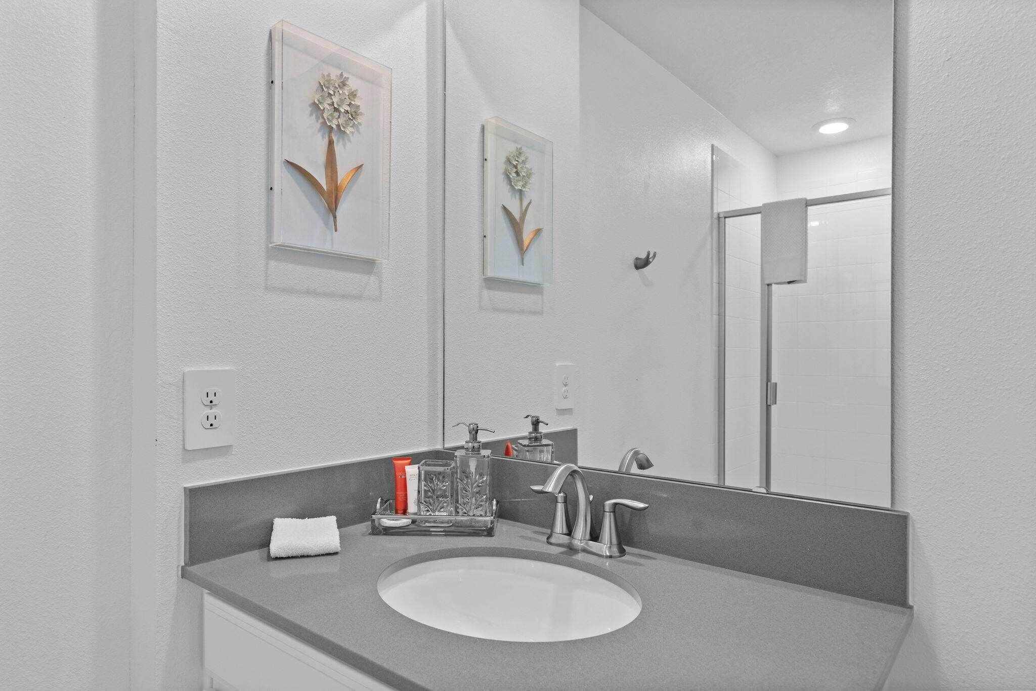 A bathroom with a white sink, a mirror, and two wall-mounted flower decorations.