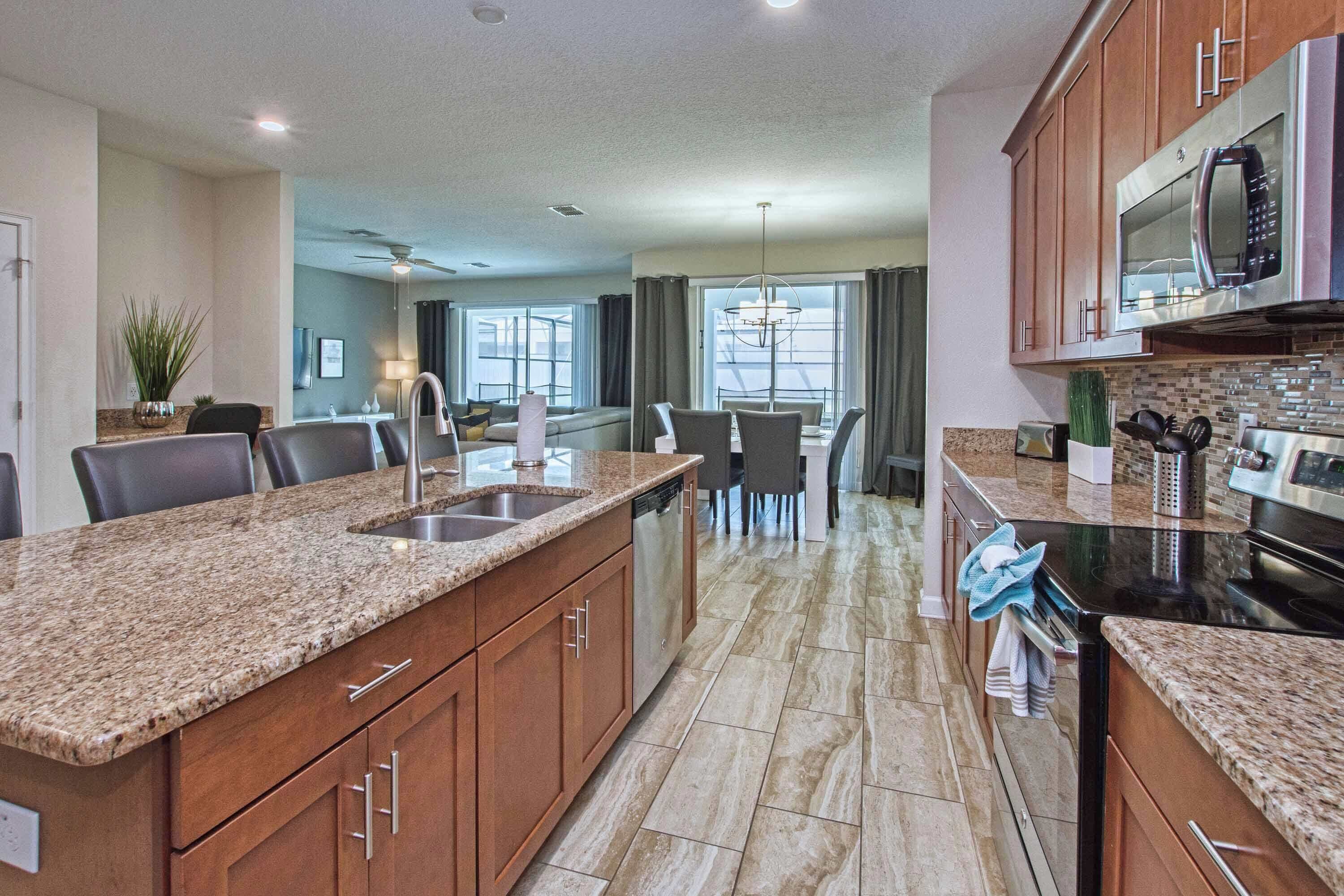 A modern kitchen with granite countertops, stainless steel appliances, and a dining area with a view.