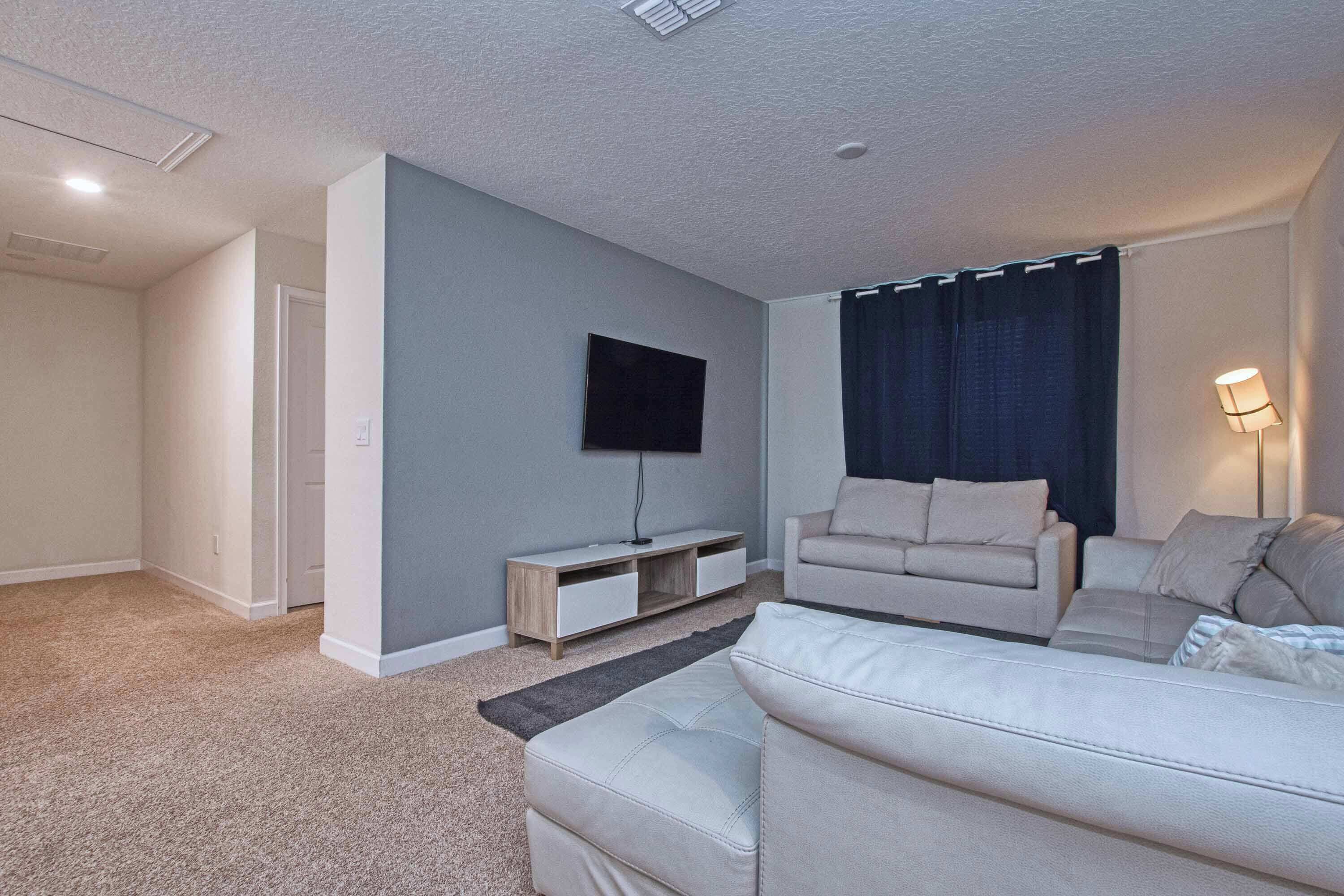 A living room with a flat-screen TV, two sofas, a coffee table, and a lamp.