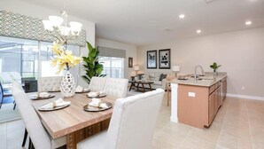 Une cuisine spacieuse dotée d’un îlot central, un coin repas avec une table en bois et un salon avec un canapé et une table basse.