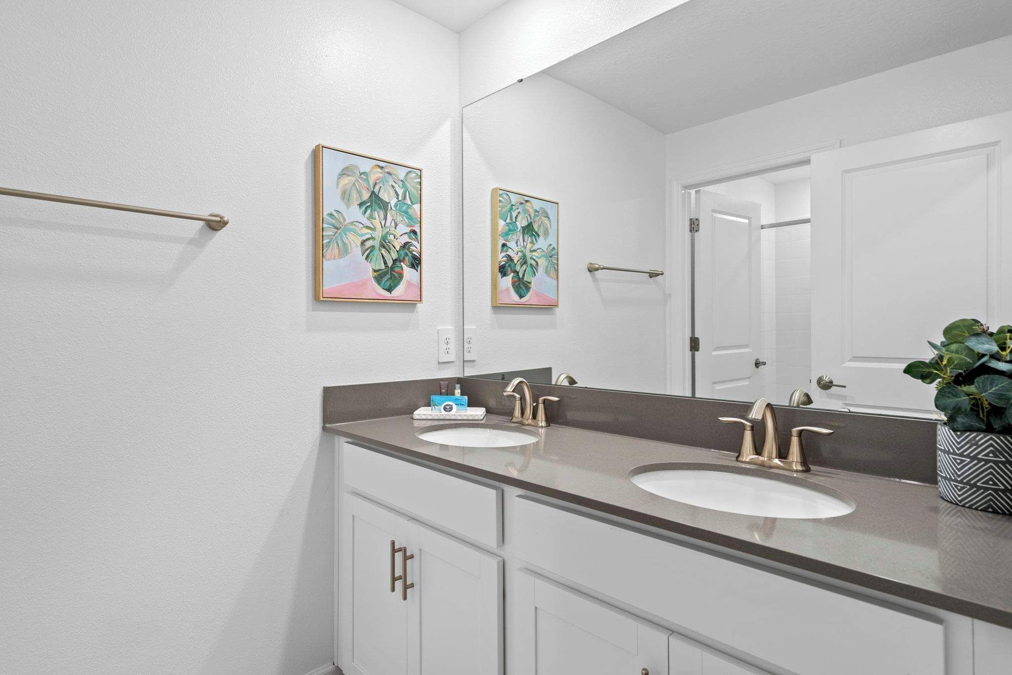 A bathroom with two sinks, a large mirror, and a towel rack.