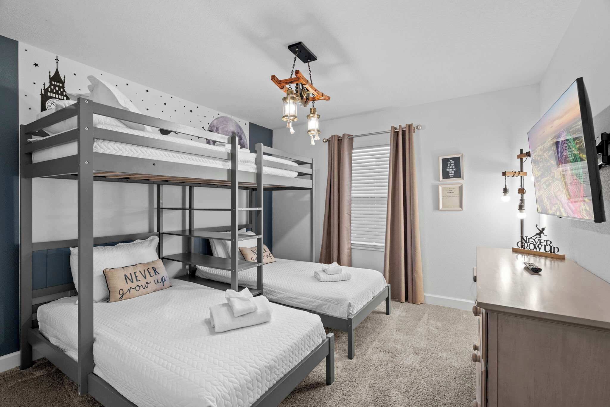 Ein Schlafraum mit Etagenbetten, einem Schreibtisch, einer Chandelier und einer Stadtlandschaft an der Wand.