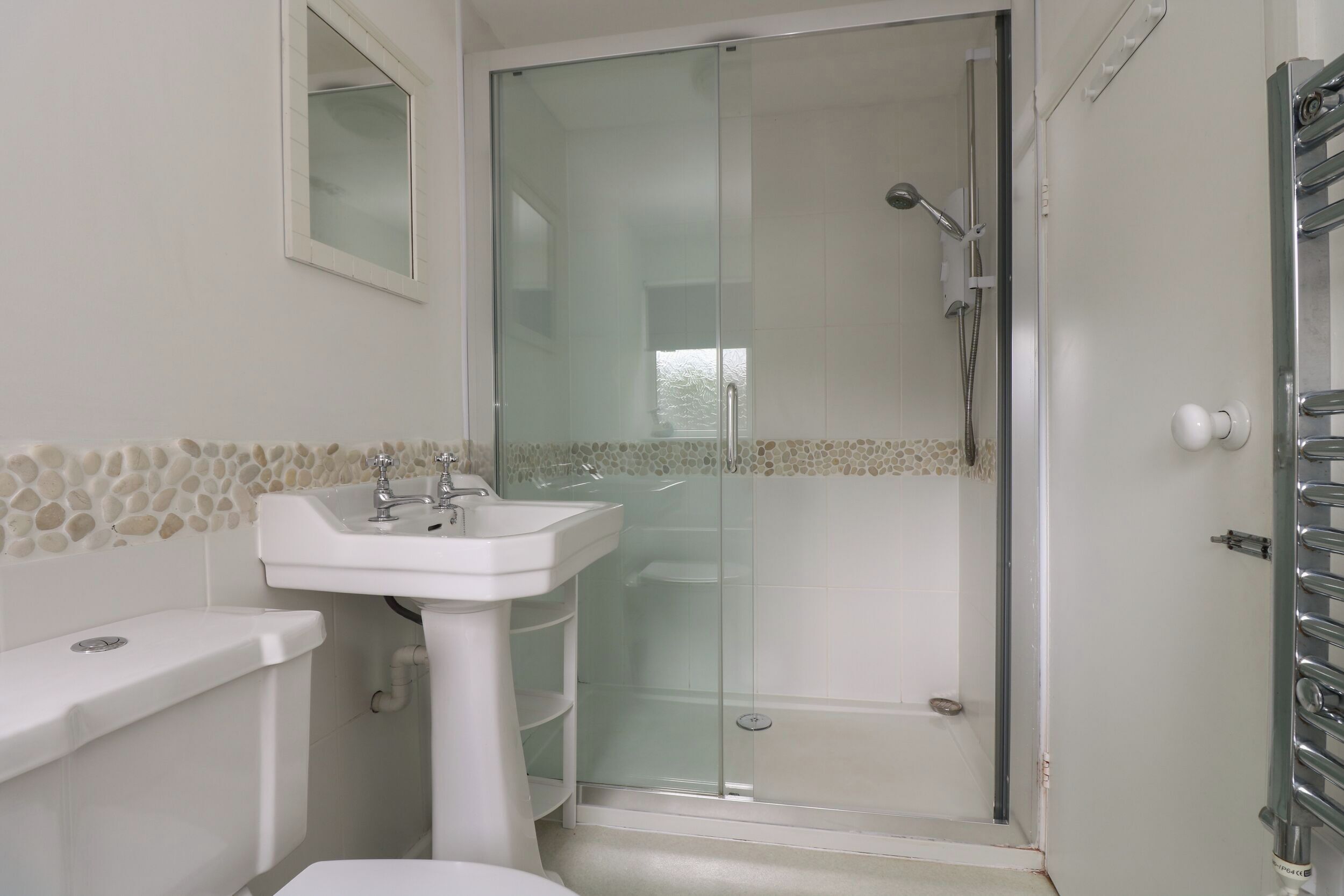 A bathroom with a glass-enclosed shower, a white sink, and a toilet.