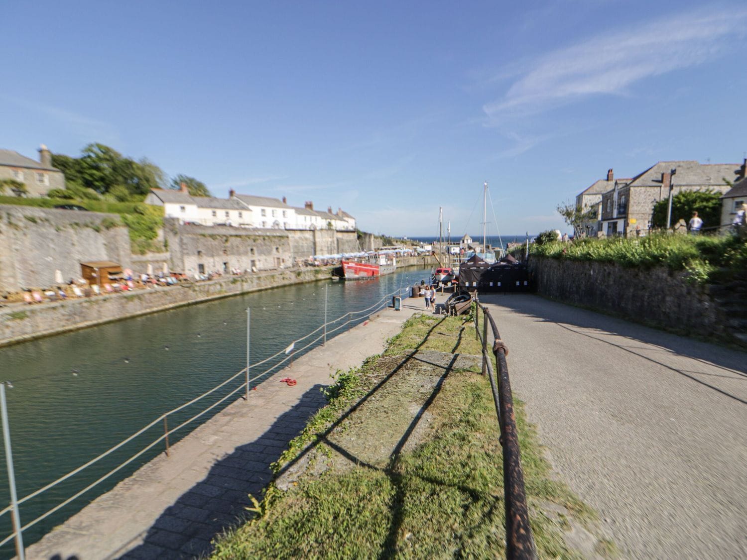 A coastal town with a narrow waterway, stone buildings, and a paved walkway alongside the water.