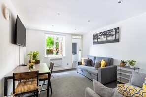 Un salon moderne avec un canapé, une table à manger et un téléviseur fixé au mur.