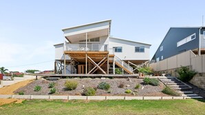 Ein modernes, zweistöckiges Haus mit einer Holzdiele und einem Balkon.