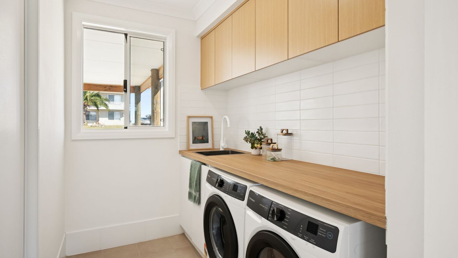 A compact kitchen with a washing machine, a sink, and wooden cabinets.