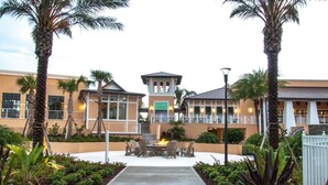 A hotel courtyard with a central fire feature, palm trees, and a covered seating area. - Sunny Retreat-colorful Home, Pool, Great Location (Kissimmee)
