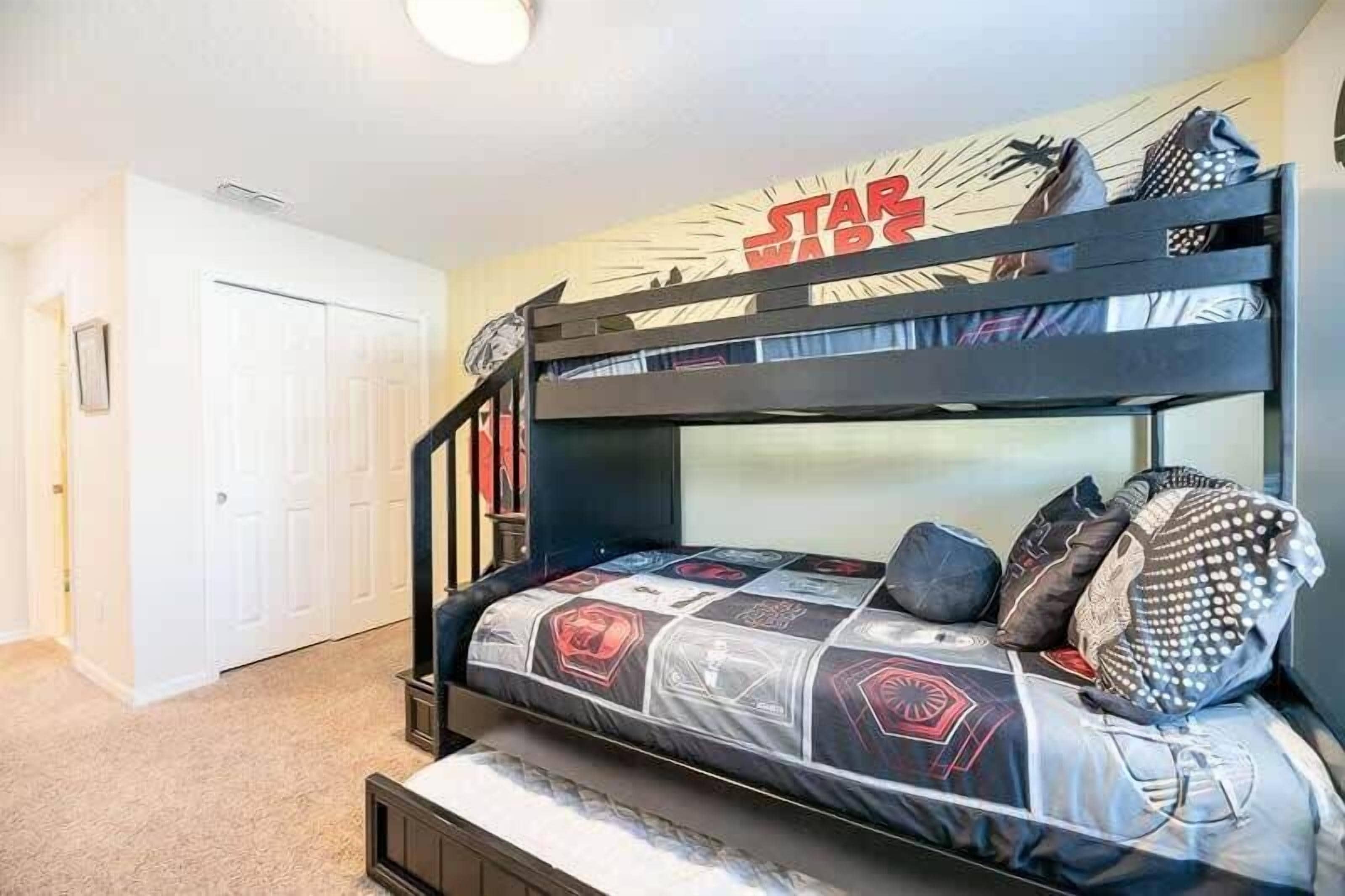 A bunk bed with Star Wars themed bedding, a white door, and a ceiling light.