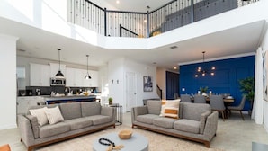 A spacious living area with two grey sofas, a round coffee table, and a dining area with chairs and a table. - Super Luxury Modern Home, Prime Location (Kissimmee)