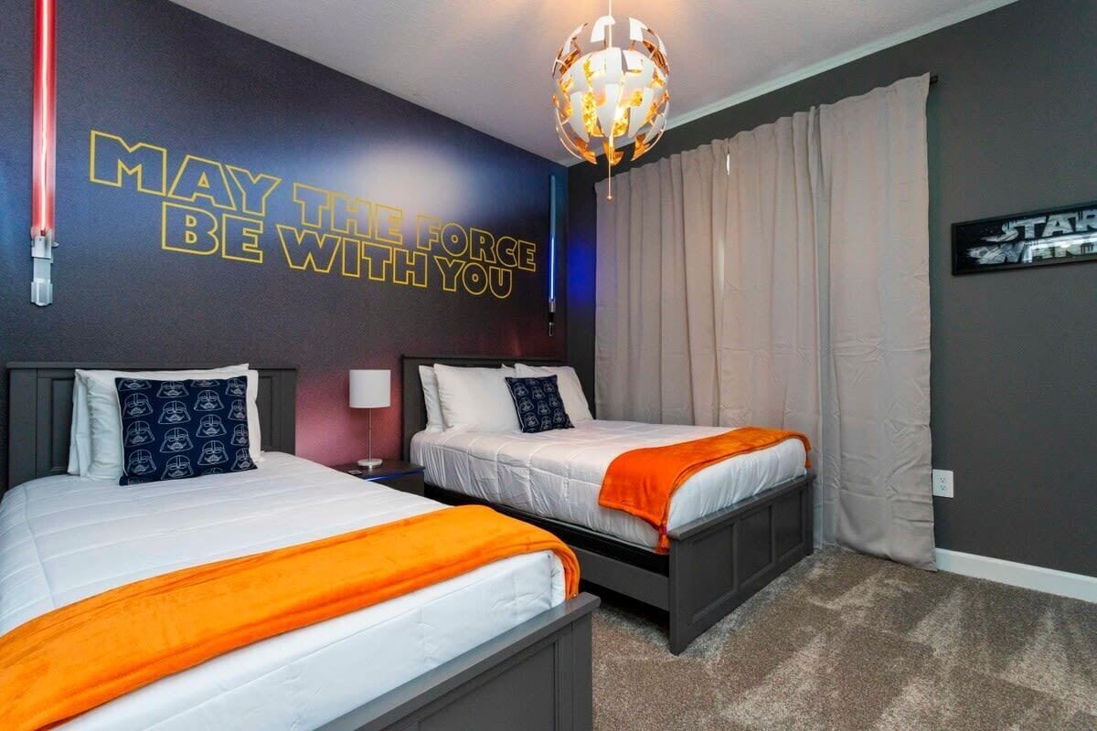 A hotel room with two beds, a Star Wars themed wall, a globe light, and a Star Wars poster.