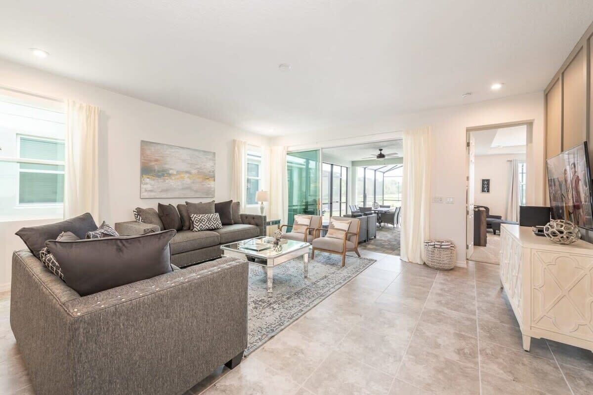 A spacious living room with a grey sofa, a coffee table, and a white cabinet.