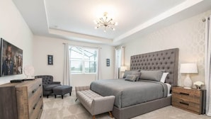A bedroom with a large bed, a dresser, a chair, and a nightstand. - Stunning Retreat, Private Pool, Perfect Location (Kissimmee)