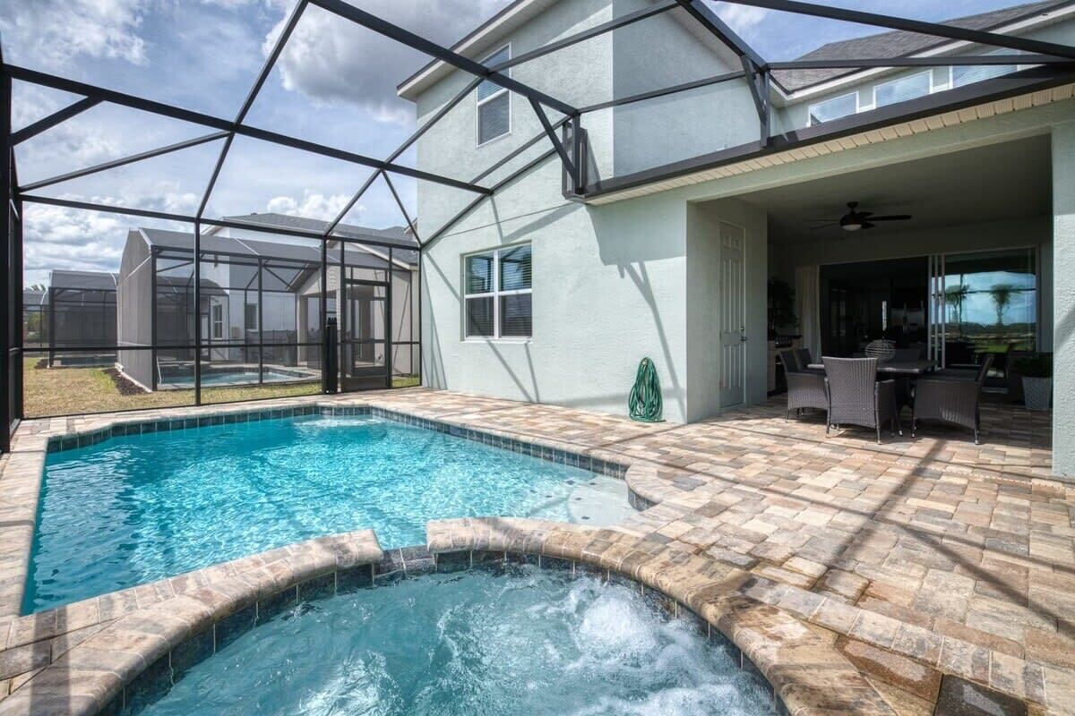 A backyard with a swimming pool, patio furniture, and a covered area with a ceiling fan.