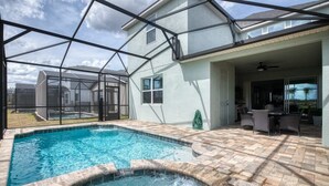 A backyard with a swimming pool, patio furniture, and a covered area with a ceiling fan. - Stunning Retreat, Private Pool, Perfect Location (Kissimmee)