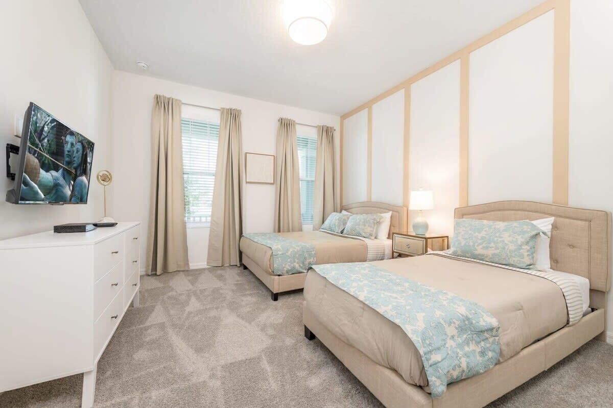 Une chambre d’hôtel avec deux lits, une télévision, une commode et une fenêtre avec des rideaux.