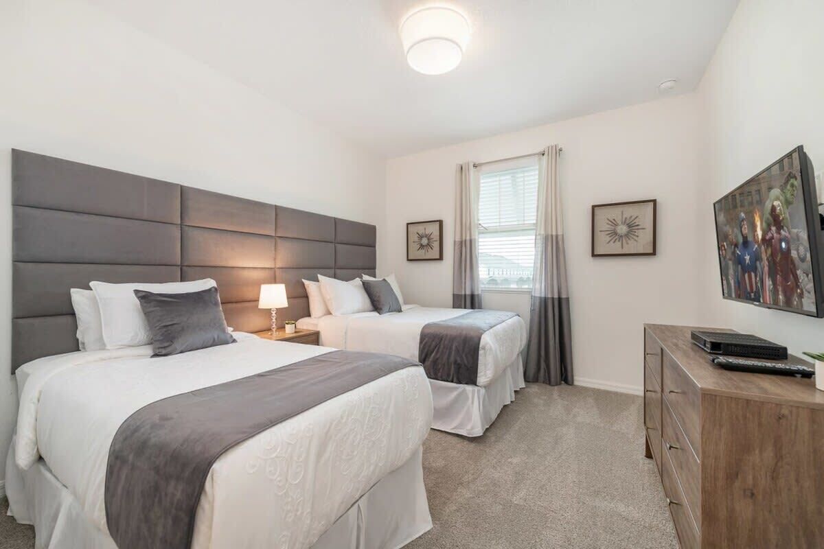 A hotel room with two beds, a wooden dresser, and a painting on the wall.