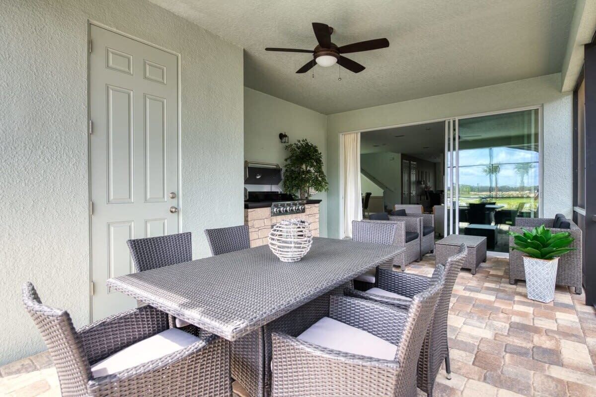 An outdoor patio with a dining table and chairs, a ceiling fan, and a view of the backyard.
