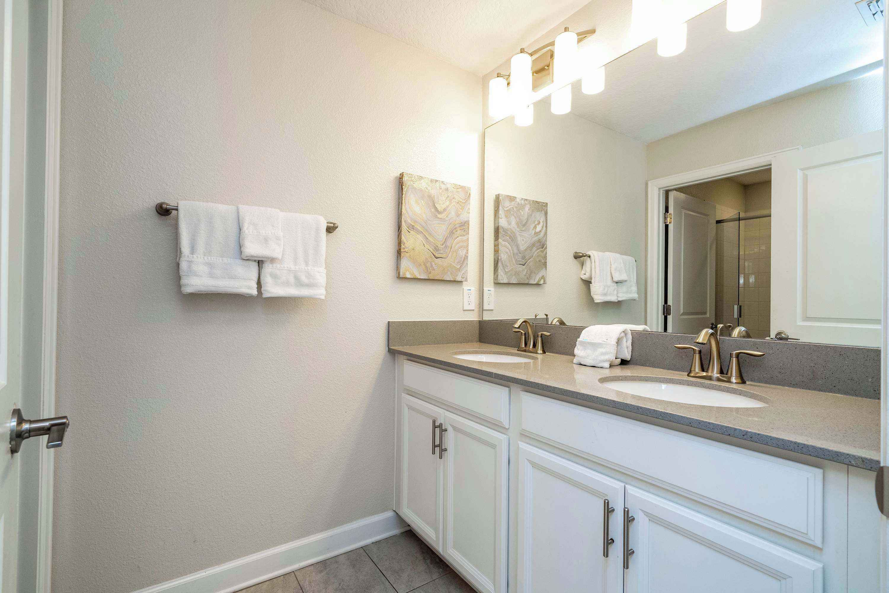 A bathroom with two sinks, a large mirror, and wall-mounted towels.