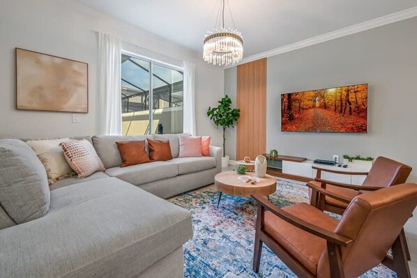 A modern living room with a sofa, armchair, coffee table, and artwork on the wall. - Ultimate Luxury Home-private Pool, Themed Bedroom (Kissimmee)