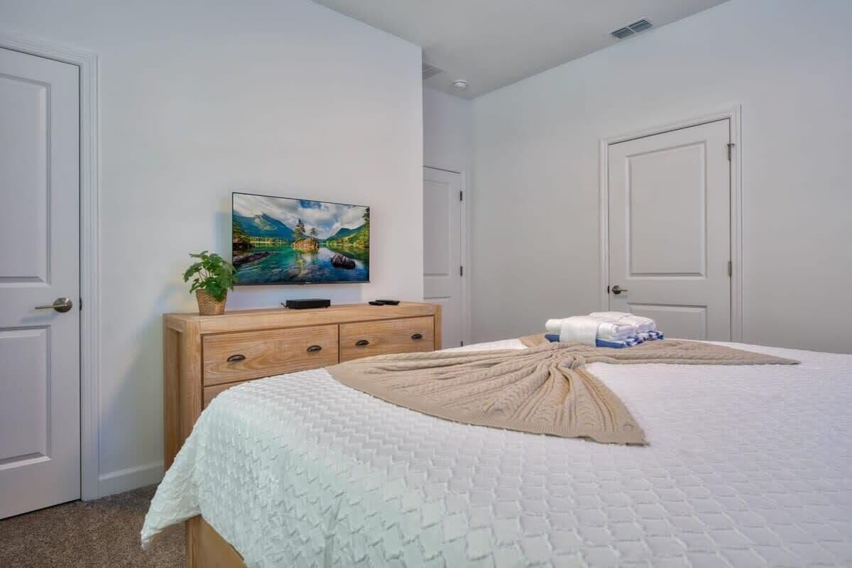 Une chambre à coucher avec un lit, une commode, un tableau et une porte.