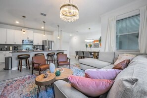 Un salon moderne comprenant un canapé, des fauteuils, une table basse et un coin repas avec une table et des chaises.