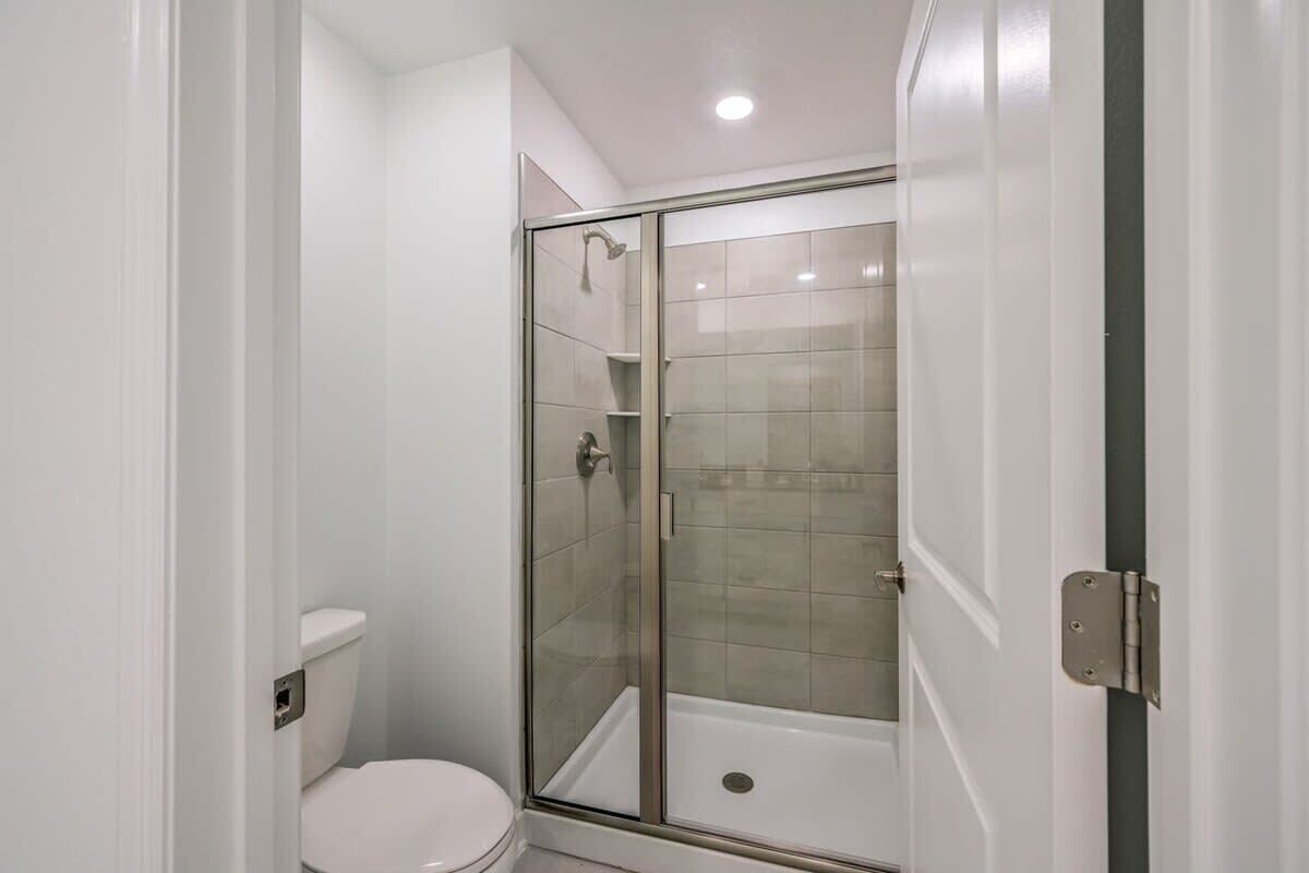 Een badkamer met een toilet, een douche met glazen deur en een bad.