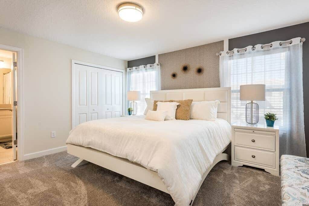 A bedroom with a bed, bedside tables, a nightstand, a ceiling light, and a door.
