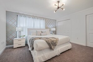 Una camera da letto con un letto grande, comodini, un appendiabiti e un lampadario.