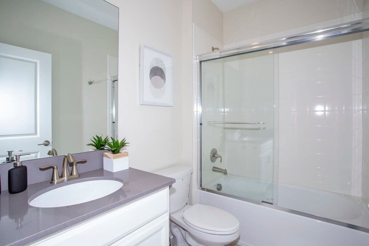 A modern bathroom with a glass-enclosed shower, a white sink, and a toilet.