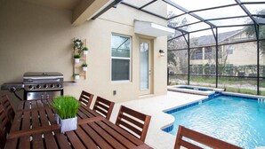Une terrasse extérieure avec une piscine, des meubles en bois, un barbecue et des plantes en pot.