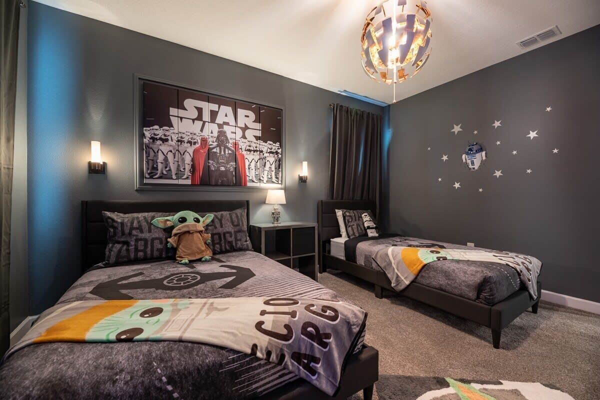 A Star Wars-themed bedroom with two beds, a Star Wars poster, and a ceiling light fixture.