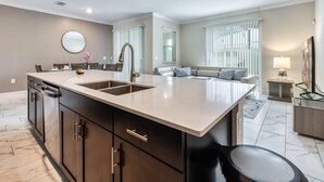 A modern kitchen with a large island, built-in appliances, and a dining area with a sofa and a side table. - Tranquil Retreat - Serene Getaway (Davenport)