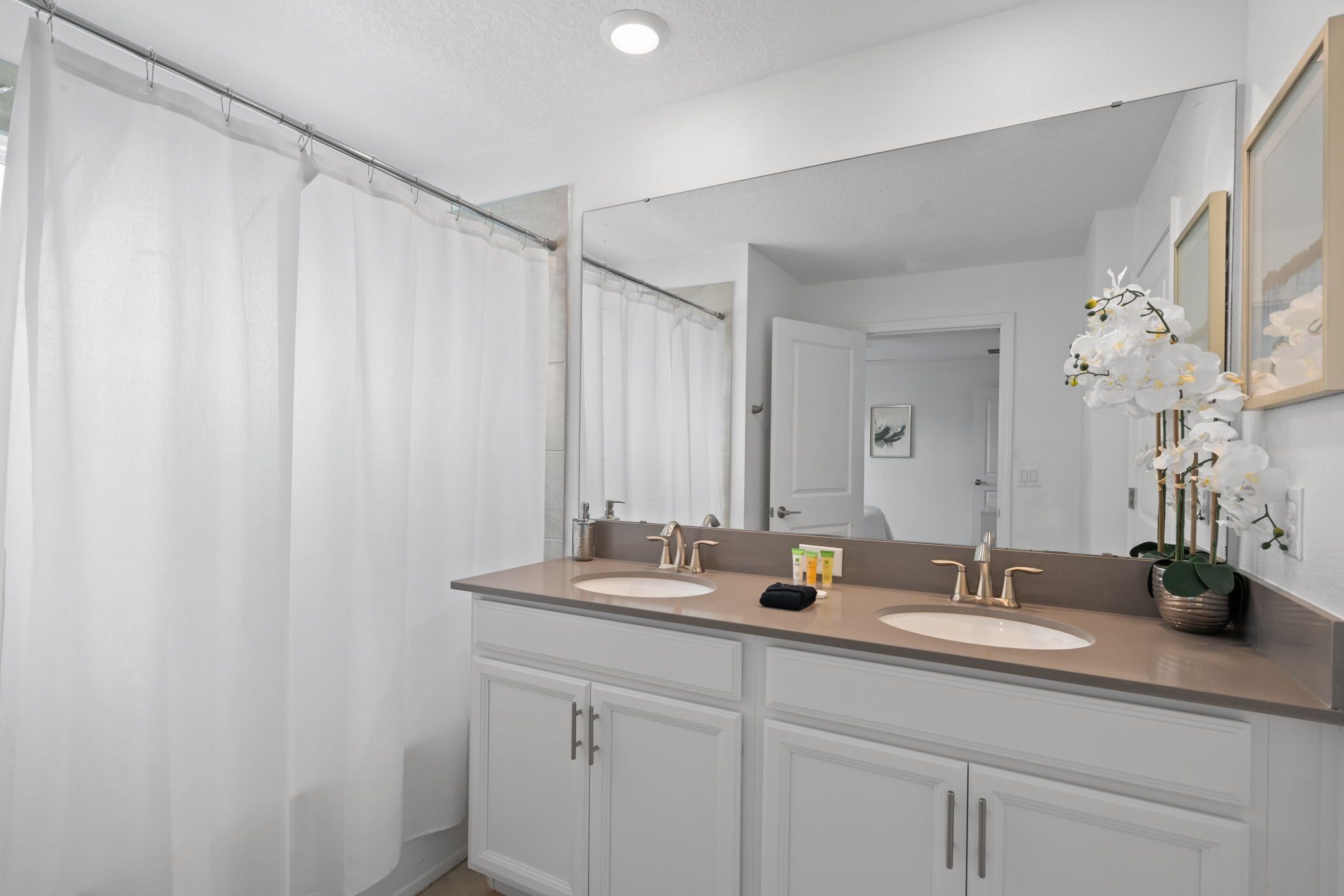 A bathroom with two sinks, a large mirror, and a shower curtain.