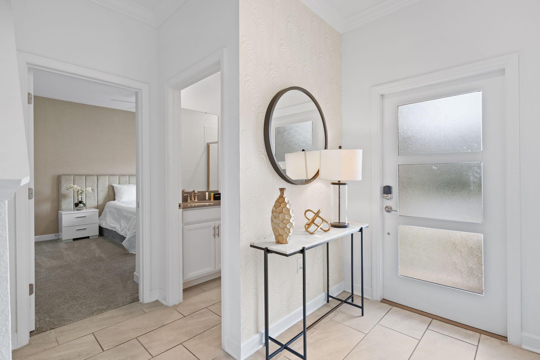 A hotel room with a bed, bedside table, lamp, and a mirror on the wall.